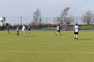 St Edmunds staff in football kit playing football on an astro turf pitch taking part in charity week